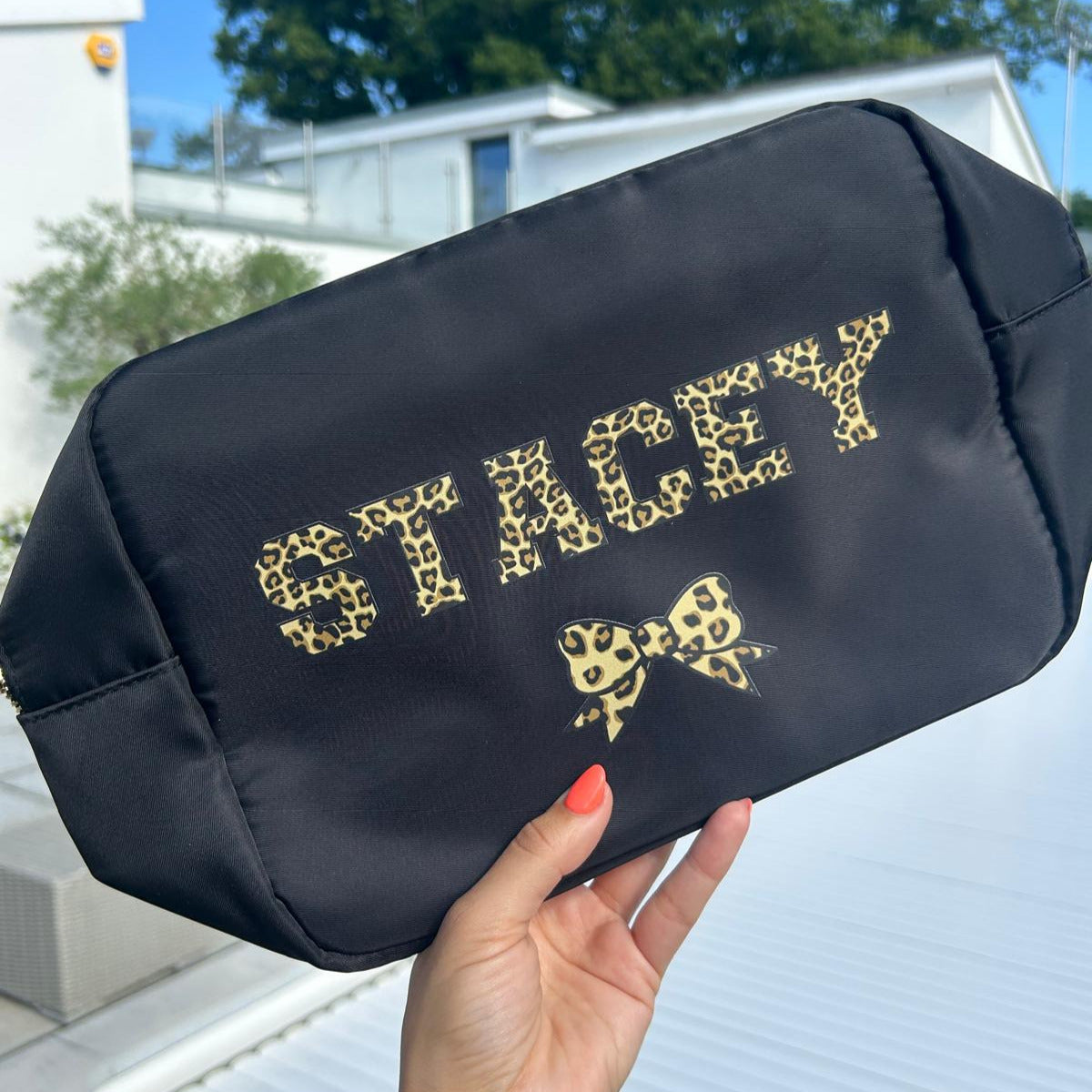 Black pouch with gold text held by a hand outdoors