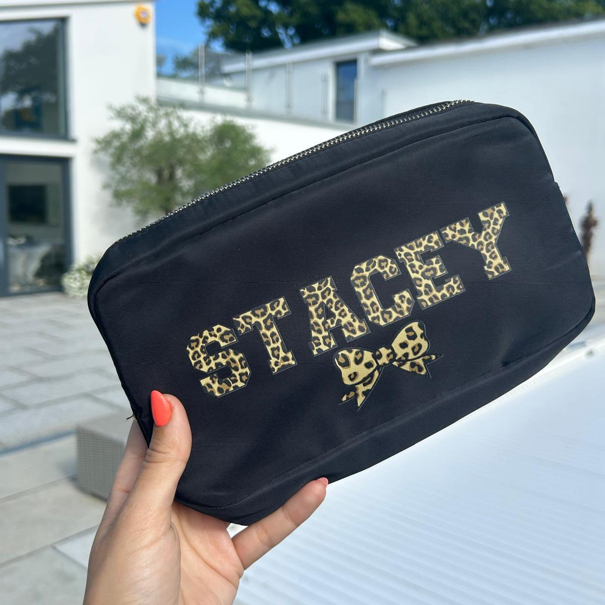 Black pouch with 'STACEY' branding held outdoors